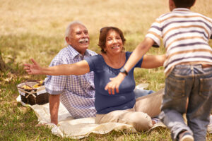 Old people, senior couple, elderly man and woman. Outdoor family having fun with happy grandpa and grandma hugging boy at picnic in park.