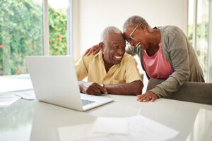 Shot of a happy senior couple smiling together with a laptop in front at home